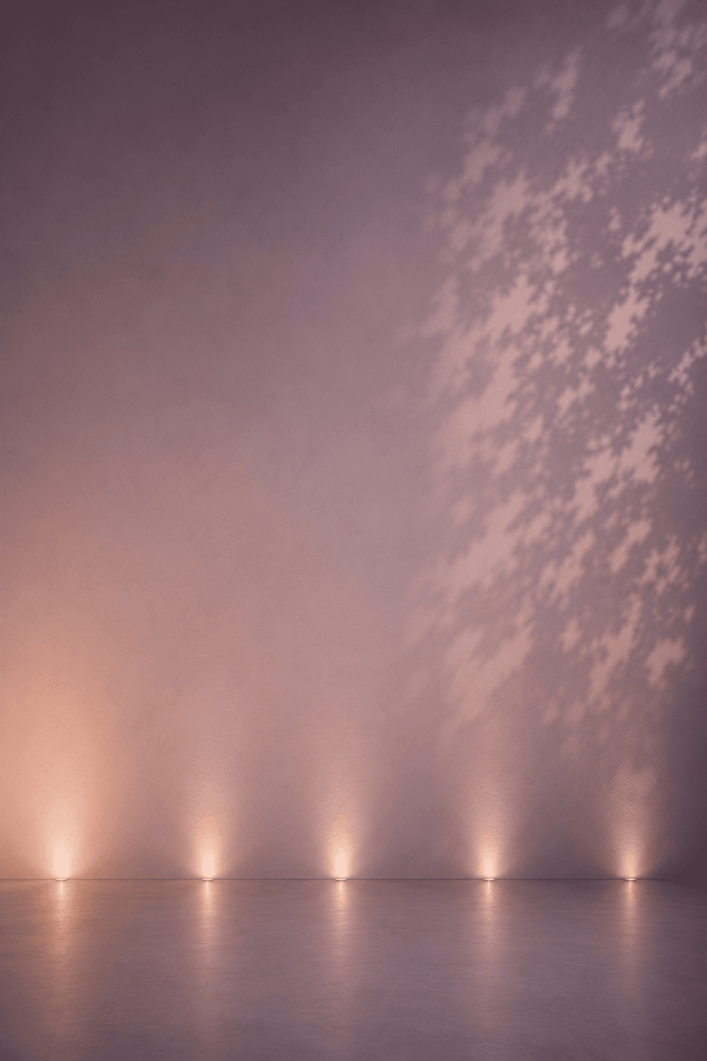 A mauve wall lit by a row of uplights along the floor.